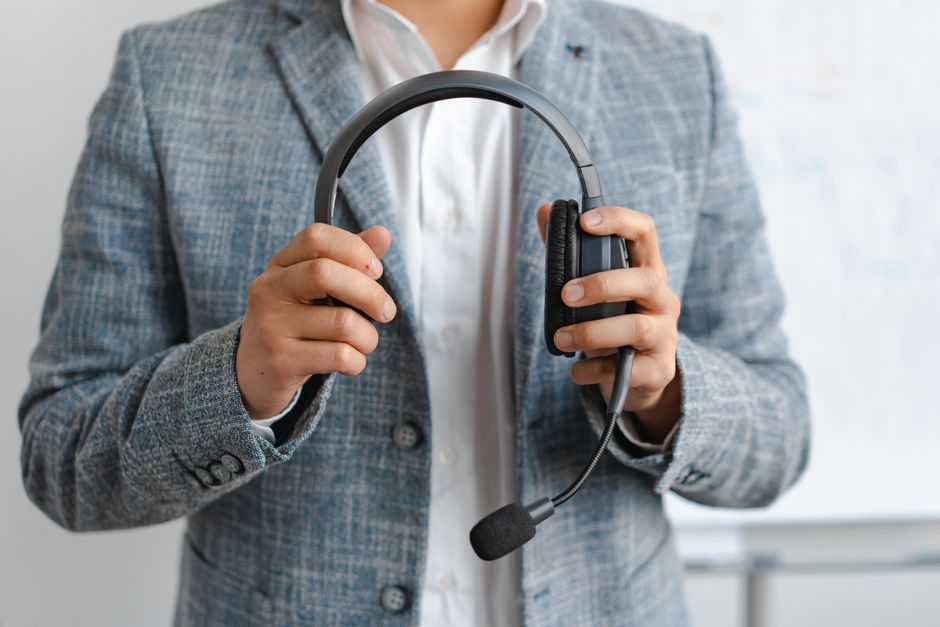 A person with noise-canceling headphones and a smartphone, walking briskly through a city park while seemingly engaged in a remote walking meeting, looking focused and productive.
