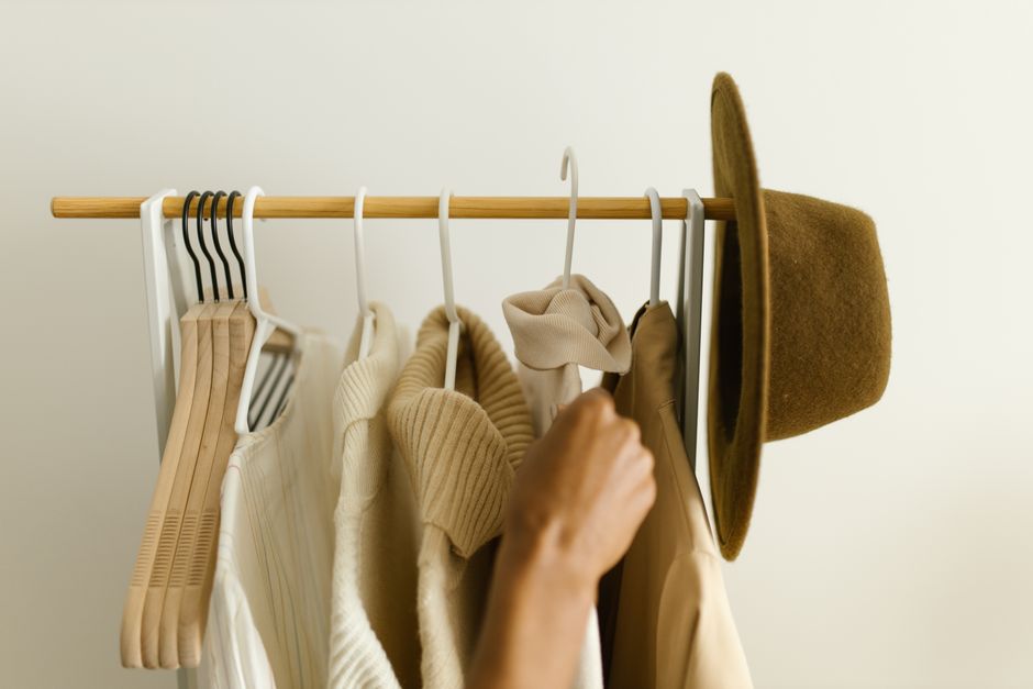 A person thoughtfully arranging high-quality, versatile clothes in a neatly organized capsule wardrobe, demonstrating smart investment.