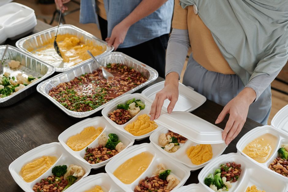 A person carefully packing a reusable lunch container with fresh salad, grilled chicken, and berries for work.