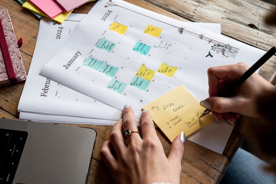 A person in an urban apartment focused on a laptop, surrounded by a planner and a cup of coffee, symbolizing goal setting and concentration.