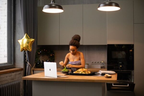 Overhead shot of a person using a notebook and tablet to plan meals on a modern kitchen island, surrounded by fresh ingredients and spices, emphasizing organization for busy weeks.