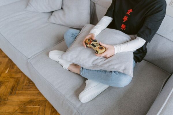 A person comfortably playing a cozy farming simulation game on a console at home, surrounded by soft lighting, illustrating relaxation after work.