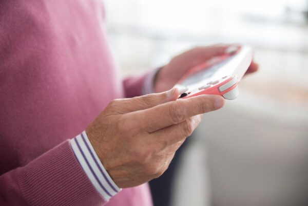 A person with headphones playing a handheld console during an airplane flight, focused on the screen.
