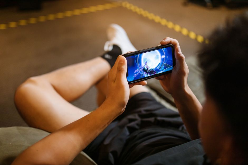 A person playing a mobile game on a smartphone in an airplane seat, focusing intently on the screen.