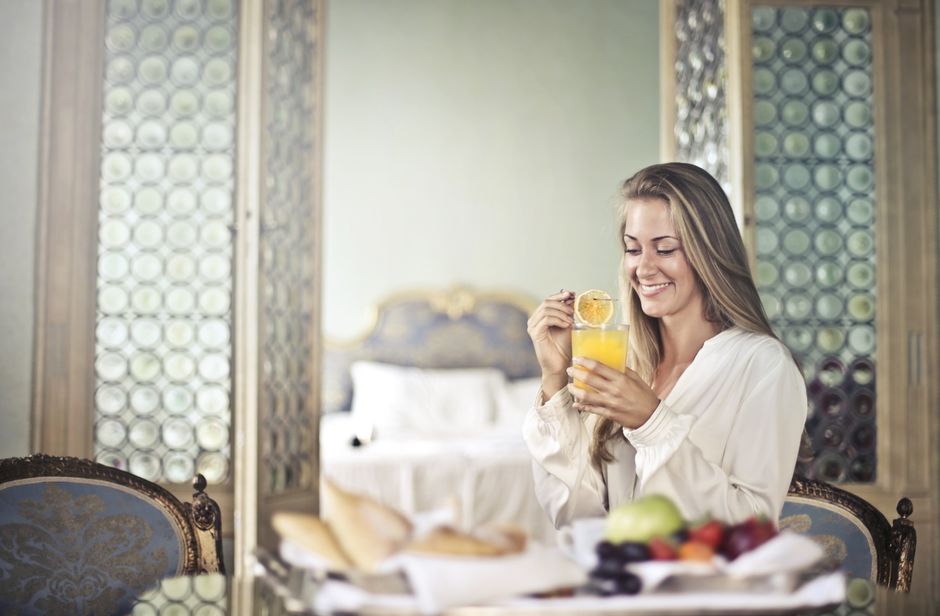 A traveler in a modern hotel room arranging a healthy breakfast of yogurt, fresh berries, nuts, and an apple on a small table, demonstrating proactive healthy travel breakfast choices.