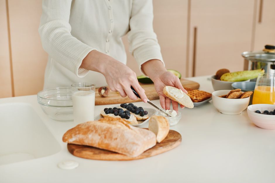 A person's hands assembling a nutritious, colorful meal in a modern kitchen, with fresh ingredients like vegetables and lean protein visible.