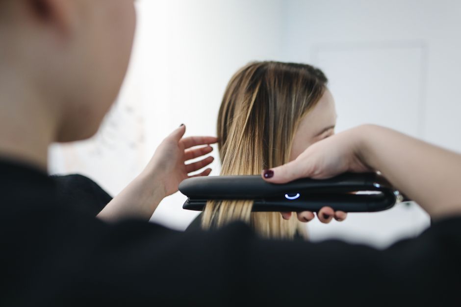 A person quickly running a brush through their hair while looking into a mirror, with a few essential makeup items on the vanity.