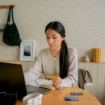 A person with a laptop and credit cards, researching options at a desk.