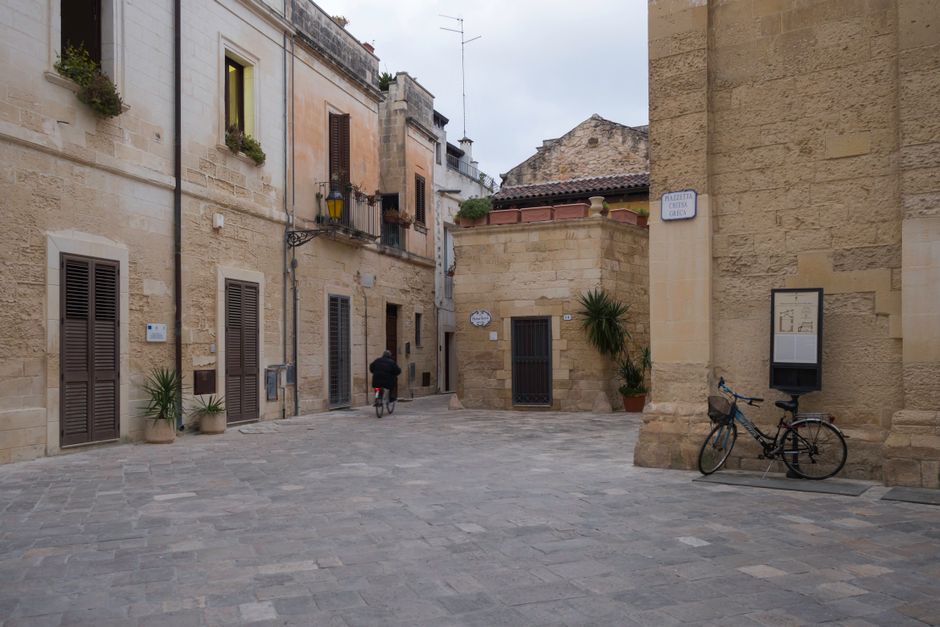 A person riding a bicycle down a charming, historic street in a European city, enjoying sustainable transport.