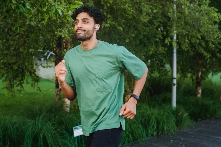 A person in athletic wear running outdoors, wearing a modern smartwatch on their wrist, tracking their workout.