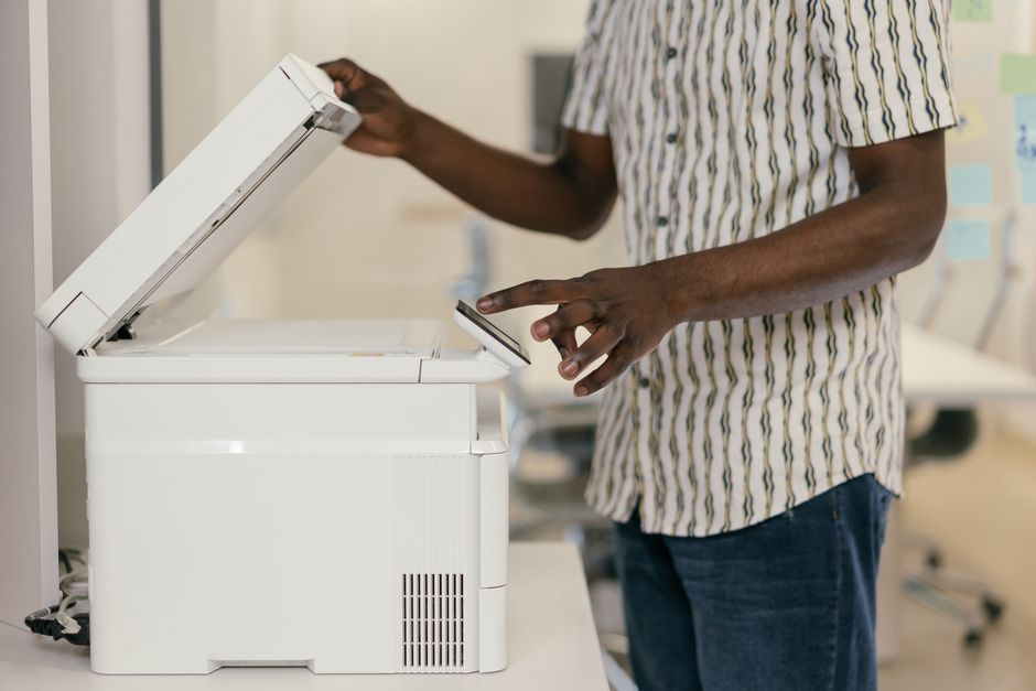 A close-up of hands using a smartphone to scan a document on a clean desk, converting paper to digital.