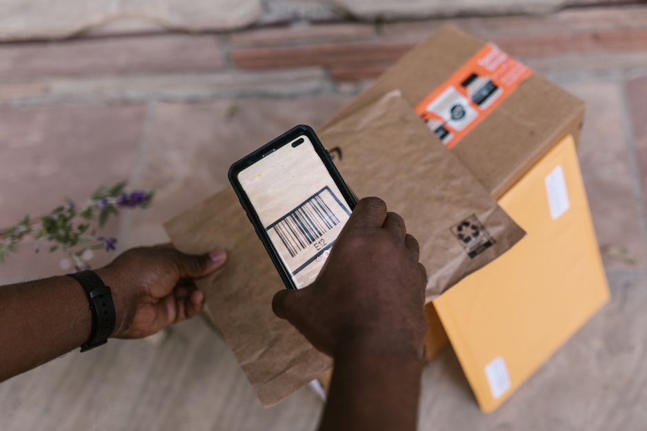 A person using a smartphone to scan a physical document on a desk, converting it into a digital file for their filing system.
