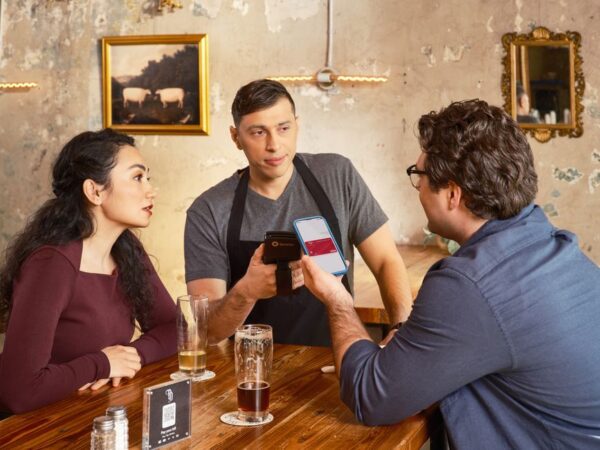A person using their smartphone to scan a QR code on a restaurant table to access a menu.