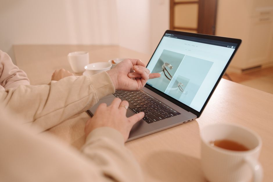 A close-up of hands hovering over a laptop keyboard, with a screen displaying multiple product reviews, some highlighted as potentially fake.