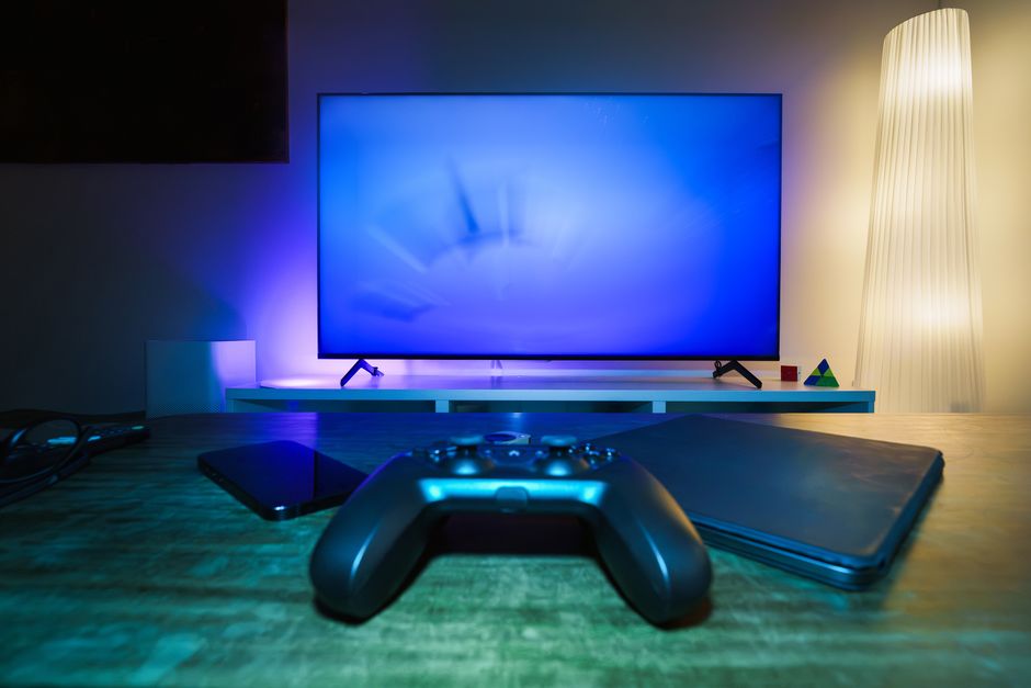A casual gamer streaming an action-adventure game on a large smart TV with a wireless controller, showing high-quality cloud gaming.