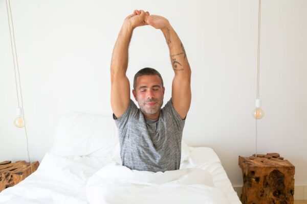 A person in comfortable clothes doing gentle stretches on a yoga mat in a sunny, modern urban apartment living room, signifying healthy morning habits without waking early.