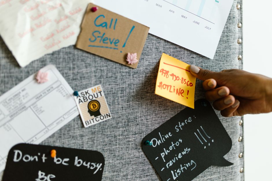 A person frustrated, surrounded by sticky notes with various handwritten passwords, symbolizing the difficulty of remembering multiple credentials.