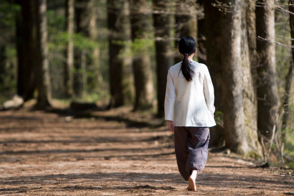 A person walking mindfully through a city park, hands in pockets, looking refreshed and focused on nature.