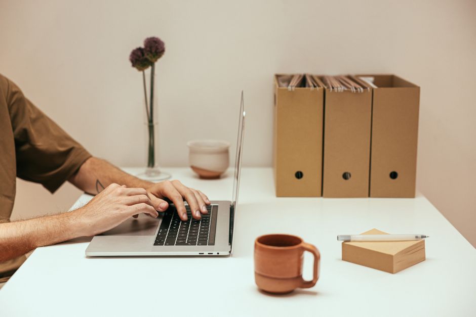 A small business owner focused on their laptop screen, actively deleting files and reorganizing folders, symbolizing the process of digital decluttering.