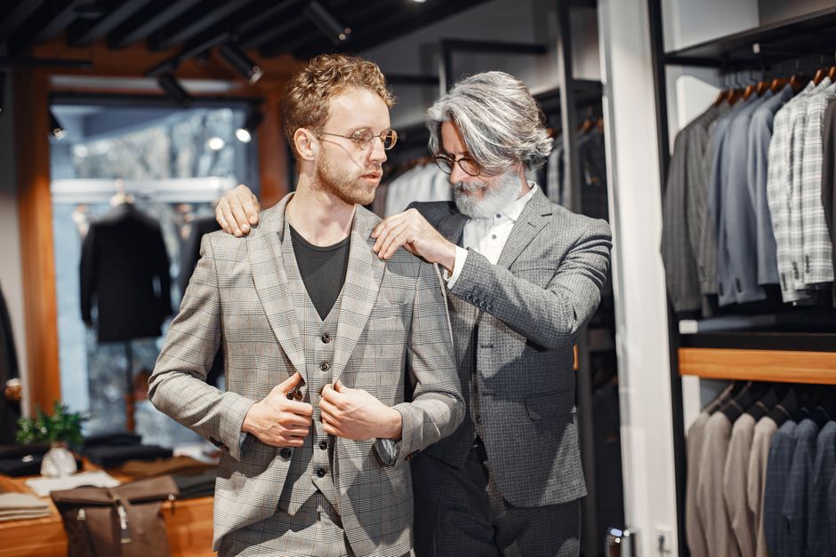 A person in a well-fitted dark blazer having the sleeves subtly adjusted by a tailor, emphasizing the importance of fit for even basic wardrobe items.