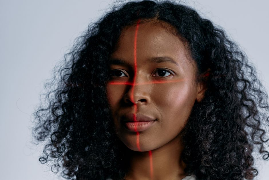 A person's face being scanned by a laptop camera for authentication, with a green checkmark indicating successful login.