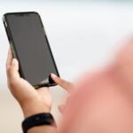 A person using a smartphone outdoors, typing a message with predictive text suggestions visible, showcasing everyday AI features in action.