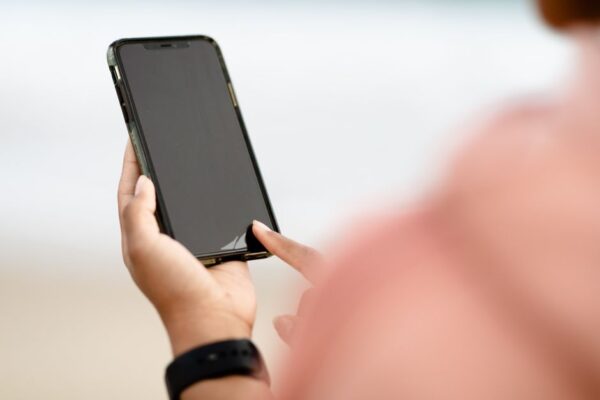 A person using a smartphone outdoors, typing a message with predictive text suggestions visible, showcasing everyday AI features in action.