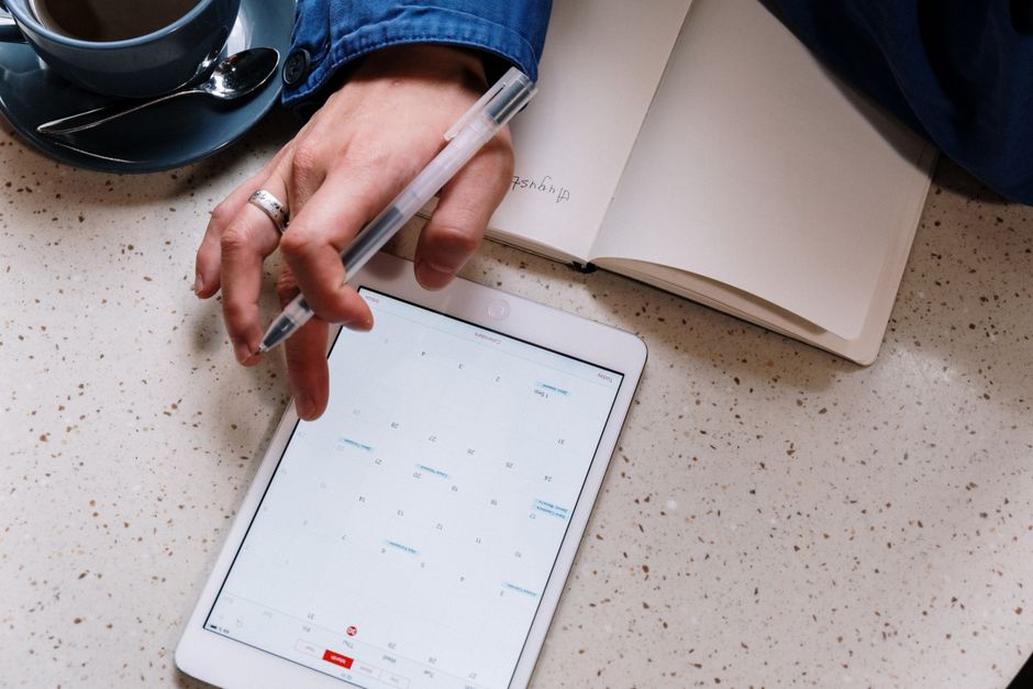 A person's hands typing on a tablet, with a digital calendar app open showing scheduled events and intelligent suggestions.