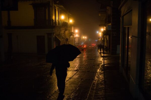 A person walking confidently through a sunny, humid city street, dressed in light, breathable fabrics.