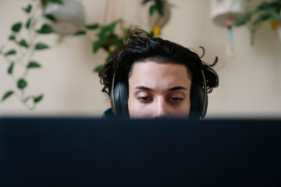 A person wearing headphones intently focused on a smartphone displaying a language learning app, possibly during a commute or study break.