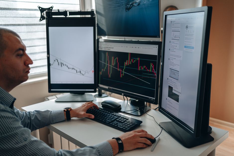 A professional working on a multi-monitor setup with two large screens displaying various applications and data, demonstrating a productive workspace.