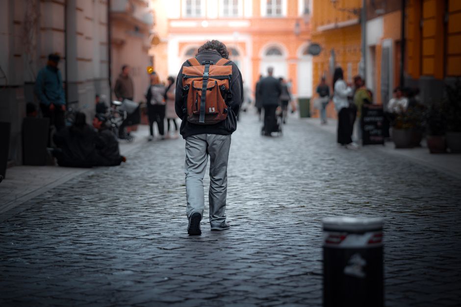 A traveler with a small, lightweight backpack walking down a historic cobblestone street in a European city, emphasizing the benefit of packing light.