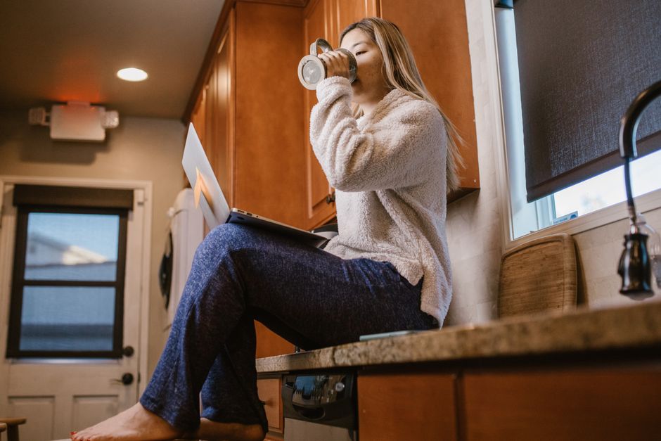 A person focused on a video call on a laptop placed on a compact kitchen island, with limited space around them but still looking professional.