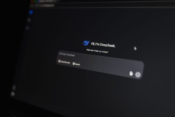 A person thoughtfully typing on a laptop, with an abstract AI interface layered over the screen, suggesting prompt creation.