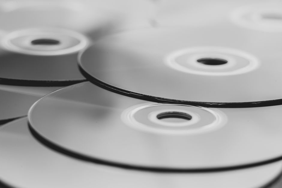 A close-up shot showcasing a collection of physical game discs and cases on one side, with a blurred background of a vibrant digital game library displayed on a screen, illustrating the two formats.