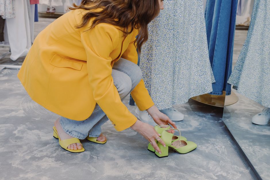 A professional, dressed in smart casual attire, sits in a shoe store, trying on a pair of supportive walking shoes, emphasizing the importance of choosing comfortable shoes for foot and back health.
