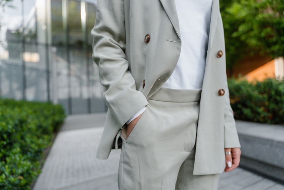 A stylish woman in a bright, airy office setting wearing wide-leg linen trousers and a breathable blouse, demonstrating practical summer workwear for hot climates.