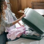 A busy professional woman efficiently packing a compact suitcase with a few versatile garments for a business trip.