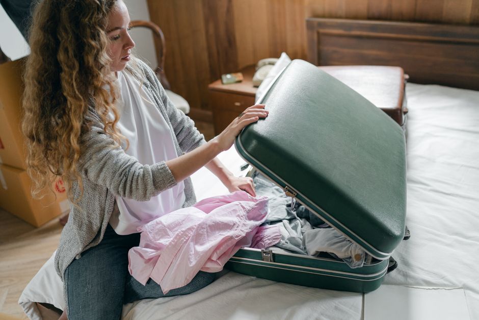 A busy professional woman efficiently packing a compact suitcase with a few versatile garments for a business trip.