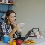 A remote worker in a bright home office, smiling while looking away from their laptop during a quick stretch break, emphasizing practical self-care.