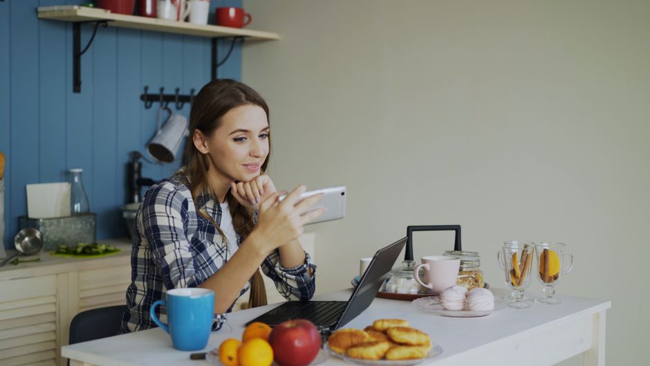 A remote worker in a bright home office, smiling while looking away from their laptop during a quick stretch break, emphasizing practical self-care.