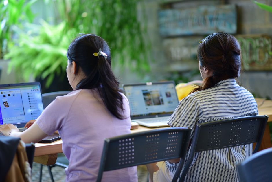 A person in front of a computer screen with a video call open, while simultaneously sharing another screen showing a movie or online game, depicting shared virtual experiences.