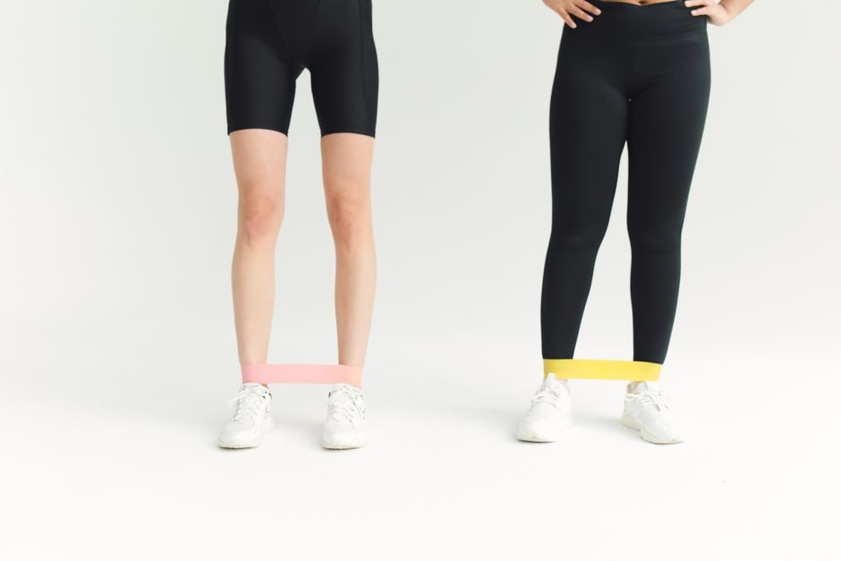Arrangement of compact workout equipment like adjustable dumbbells, resistance bands, and a rolled-up yoga mat, neatly stored against a wall in a small apartment.