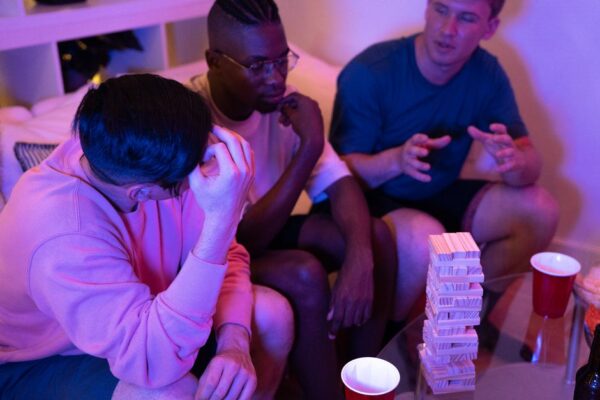 Three roommates chatting comfortably in a tidy, modern living room, representing positive communication in a shared apartment.