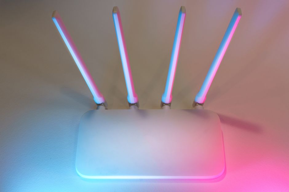 A close-up of a modern Wi-Fi router with a digital shield icon overlayed, symbolizing network protection.