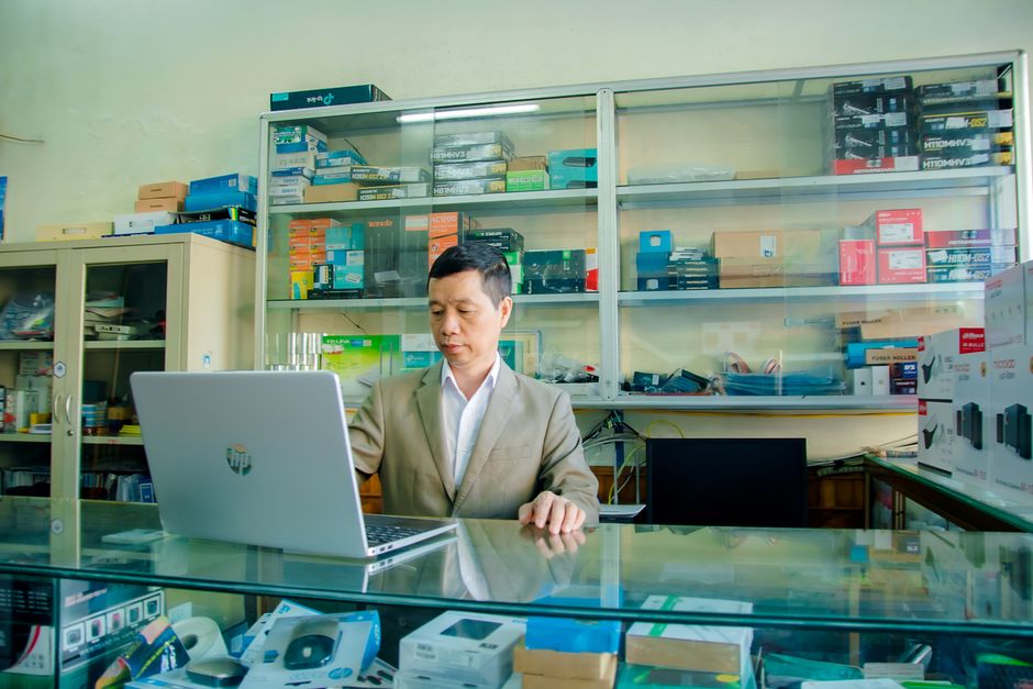 A small business owner meticulously inspecting the screen and keyboard of a refurbished laptop, making sure it meets quality standards.