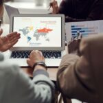 A small business owner using a laptop with a global map overlay, planning international business trips, symbolizing AI for trip planning.