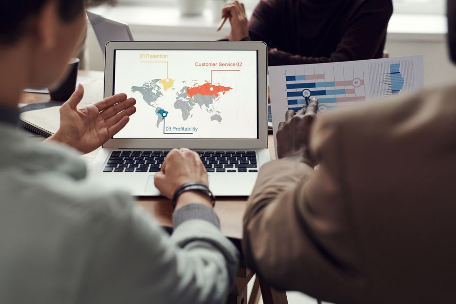 A small business owner using a laptop with a global map overlay, planning international business trips, symbolizing AI for trip planning.