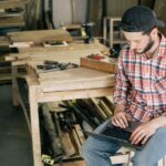 A small business owner looking thoughtfully at an old silver laptop, considering its future.