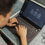 A small business owner smiling at her laptop screen, which displays a friendly AI chatbot assisting a customer.